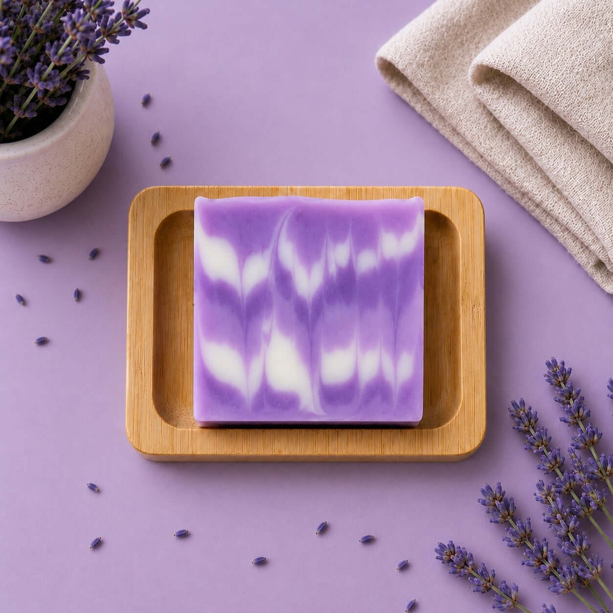 Bio Seife 'Lavendel' auf einer Bambusholzablage mit Lavendelblüten im Hintergrund.